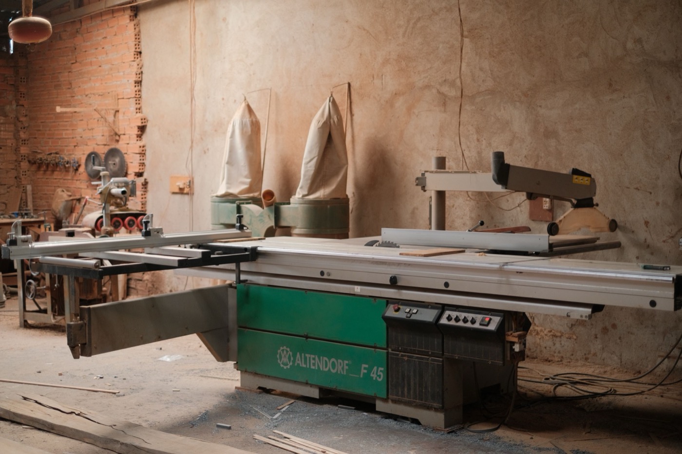 A small woodworking shop with a bag-style dust collector and sliding table saw